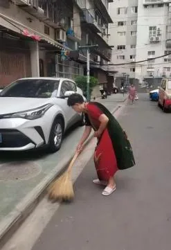桂姐退休后在小区里清扫道路
